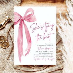 May include: A pink watercolor bow with the text "She's tying the knot" on a white card. The card also includes the bride-to-be's name, the date and time of the wedding, the location, and RSVP information. The text "Registered at Amazon & Target" is also included.