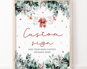 Pode incluir: Um sinal imprimível com um design de aquarela de vegetação, flocos de neve e roupas de bebê penduradas em um varal. O texto no sinal diz "Custom sign" e "Add your own custom message here".