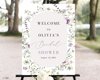 May include: A white welcome sign with a floral border and a light gray circle in the center. The text reads "Welcome to Olivia's Bridal Shower August 22, 2023".