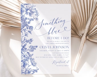 May include: A white invitation card with blue floral design and text that reads "Something Blue Before I Do!" for a bridal shower. The invitation includes the bride's name, date, time, and location. Registered at Amazon & Target.