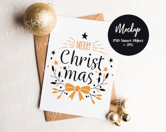 May include: A white card with a gold and black design that says "Merry Christmas" with a bow and stars. The card is on a brown envelope and a white surface.