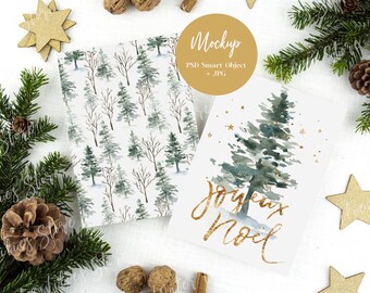 May include: A Christmas card mockup with a watercolor illustration of a pine tree with gold glitter stars and the text "Joyeux Noel" in gold glitter. The card is on a white background with pine branches, walnuts, and gold stars.