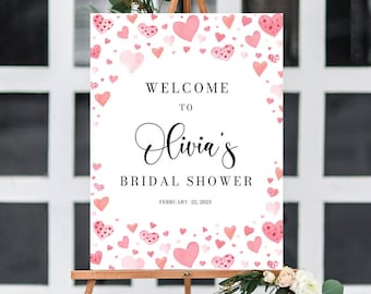 Könnte beinhalten: Ein weißes Willkommens-Schild für eine Bridal Shower mit rosa Aquarellherzen und dem Text "Willkommen zu Olivia's Bridal Shower Februar 22, 2023".