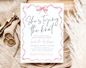 Könnte beinhalten: Eine weiße Brautduscheinladung mit rosa Schleifenakzenten. Die Einladung lautet "She's tying the knot" und enthält den Namen der Braut, das Datum, die Uhrzeit und den Ort der Dusche. Sie enthält auch den Text "Registered at Target & Amazon".