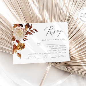 May include: A white RSVP card with a floral design featuring brown and white flowers. The card has a section for guests to indicate their attendance and meal choice. The text on the card reads "RSVP" and "Kindly respond by August 10, 20xx".