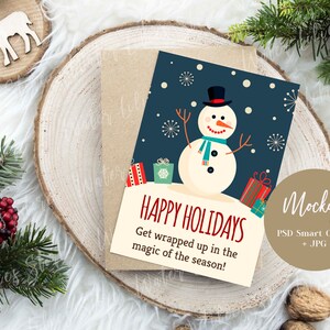 May include: A Christmas card mockup featuring a snowman with a blue scarf and hat, surrounded by presents. The card has a blue background with white snowflakes and the text "Happy Holidays Get wrapped up in the magic of the season!"