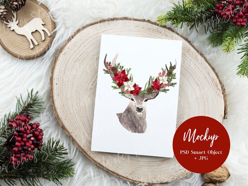 May include: A watercolor illustration of a deer with a floral crown made of red and white flowers. The illustration is on a white card, which is sitting on a wooden slice. The card is surrounded by greenery and a red circle with the text "Mockup PSD Smart Object + JPG".