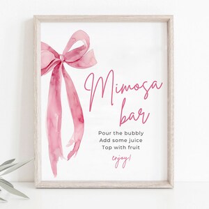 May include: A printable sign with a pink watercolor bow and the text "Mimosa Bar" in pink script. The sign also includes the instructions "Pour the bubbly, Add some juice, Top with fruit, enjoy!"