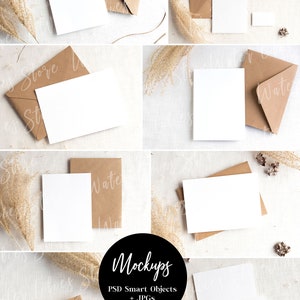 May include: Mockup of a blank white card with a brown envelope on a white textured background. The card is surrounded by dried pampas grass and other natural elements. The text "Mockups" is written in black on a white circle. The text "PSD Smart Objects + JPGs" is written in black below the circle.