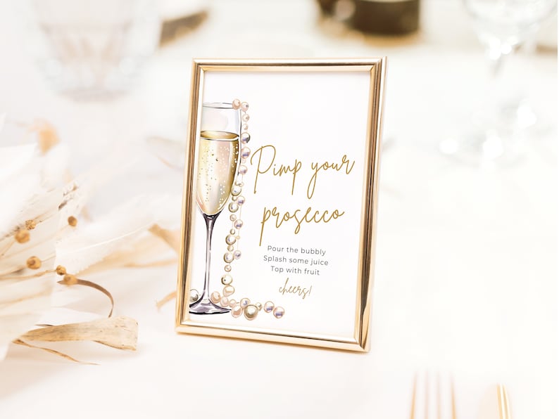 May include: A gold-framed sign with a glass of champagne and a pearl necklace. The sign reads "Pimp your prosecco" and includes instructions to "Pour the bubbly, Splash some juice, Top with fruit, Cheers!"