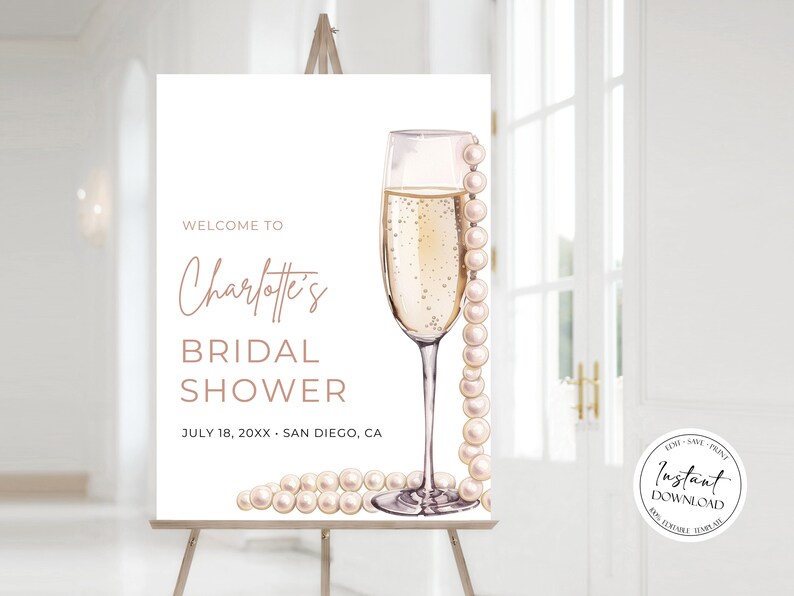 May include: A white welcome sign for a bridal shower with the text "Welcome to Charlotte's Bridal Shower" and the date "July 18, 20XX" and location "San Diego, CA". The sign features a champagne flute with a pearl necklace draped over it.