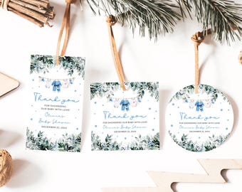 May include: Baby shower thank you tags in rectangular, square, and circular shapes. Each tag features a blue and white design with a clothesline of baby clothes and the text "Thank you". The tags are adorned with greenery and snowflakes.