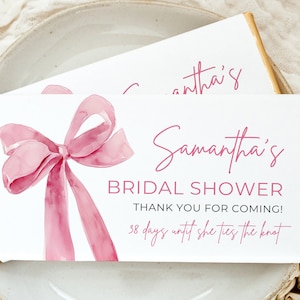 Könnte beinhalten: Eine weiße Karte mit rosa Text und einer Aquarell-Illustration einer rosa Schleife. Der Text lautet "Samantha's Bridal Shower Thank You for Coming! 38 days until she ties the knot."