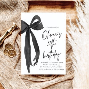 May include: A white invitation card with a black watercolor bow and text that reads "Olivia's 30th birthday." The invitation includes the date, time, and location of the event. The card is on a wooden tray with a beige cloth and gold wax seals.