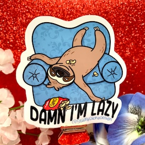May include: A sticker featuring a cartoon sloth lying in a blue armchair with a bag of chips and the text "DAMN I'M LAZY @StickyDickyDesign".