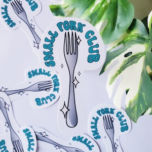 May include: Multiple white stickers with a teal blue design. The stickers feature a silver fork with a sparkling effect and the text "Small Fork Club".