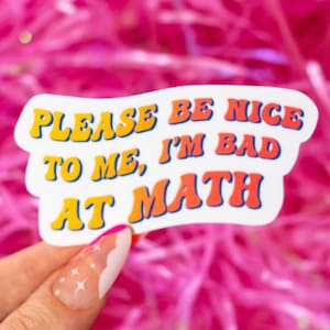 May include: White sticker with the text "Please be nice to me, I'm bad at math" in a retro font with yellow, orange, and blue colors.