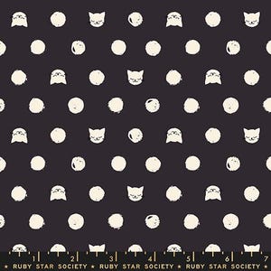 May include: A dark charcoal fabric featuring a repeating pattern of off-white cat faces and textured circular dots. A ruler at the bottom edge shows measurements in inches, with the text Ruby Star Society printed repeatedly along the bottom margin.