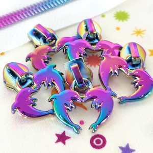 May include: A set of six iridescent zipper pulls featuring a dolphin design. The pulls are made of metal and have a rainbow finish.