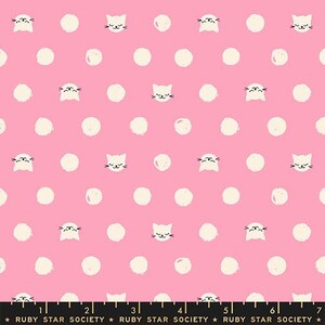 May include: A pink fabric featuring a repeating pattern of white circular dots and small white cat faces with black whiskers and eyes. A black measuring tape at the bottom shows a scale of 7 inches with the text Ruby Star Society printed.