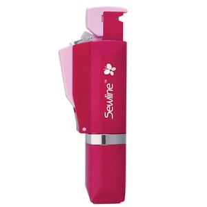 May include: A magenta and light pink Sewline fabric glue pen with a butterfly logo and the text Sewline printed vertically on the side. The device features a rectangular body, a silver-colored ring near the base, and a mechanical top mechanism.