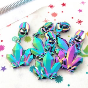 May include: Five iridescent zipper pulls shaped like crystal clusters. The pulls are a mix of blue, green, purple, and pink.
