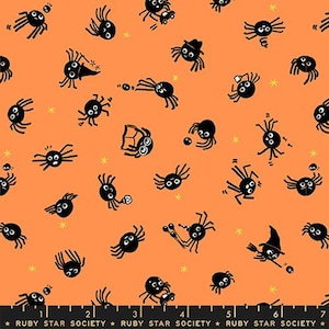May include: An orange fabric featuring a repeating pattern of black cartoon spiders in various activities, including reading, wearing hats, and holding items. A black ruler at the bottom shows measurements up to 7 inches, labeled Ruby Star Society.