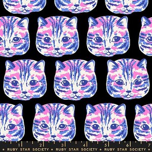 May include: A black fabric featuring a repeating pattern of cat faces in shades of pink, blue, and white. At the bottom, a ruler is visible with markings from 1 to 7 inches, accompanied by the text Ruby Star Society printed repeatedly.