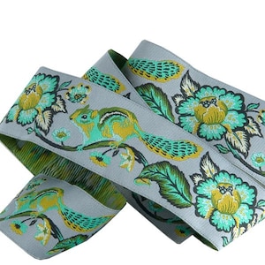 May include: Gray ribbon with a green and yellow floral pattern and a squirrel design. The ribbon is folded in half and the pattern is visible on both sides.