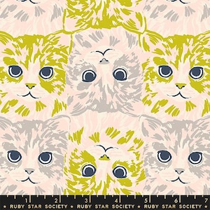 May include: A fabric pattern featuring repeating cat faces in shades of chartreuse, light pink, and grey on a pale pink background. The cats are oriented in alternating directions. A black ruler at the bottom shows 7 inches of length.