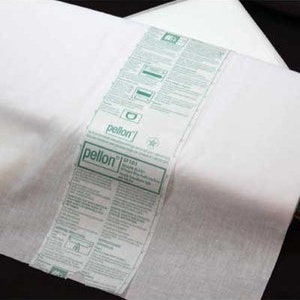 May include: A folded sheet of white Pellon SF101 Shape-Flex fusible interfacing. The fabric features a central paper band with green text and instructional icons, detailing the product name and usage guidelines for this sewing material.