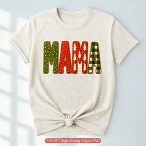 Könnte beinhalten: Cremefarbenes T-Shirt mit dem Wort "MAMA" in einem festlichen Design. Die Buchstaben sind mit grünen Punkten, Rot mit weißen Weihnachtsbäumen und grün-schwarzen Karomustern verziert. Das Shirt ist an der Taille gebunden.