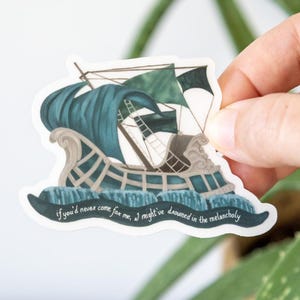 May include: A sticker depicting a stylized ship with teal waves and sails. The ship has a decorative design and the text "if you'd never come for me, I might've drowned in the melancholy" is written across the bottom. The sticker is held by a hand.