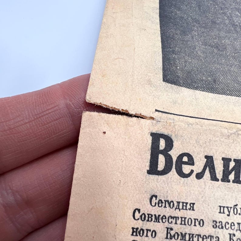 May include: Close-up of a torn, aged newspaper page with Russian text. The word "Вели" is prominently displayed in bold, black letters. The paper has a beige hue with visible wear and tear, suggesting age.