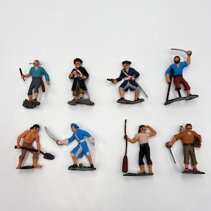 May include: Set of eight plastic pirate figurines, each with a different pose and accessories. The figurines are painted in various colors, including blue, red, brown, and black. They are standing on small bases.