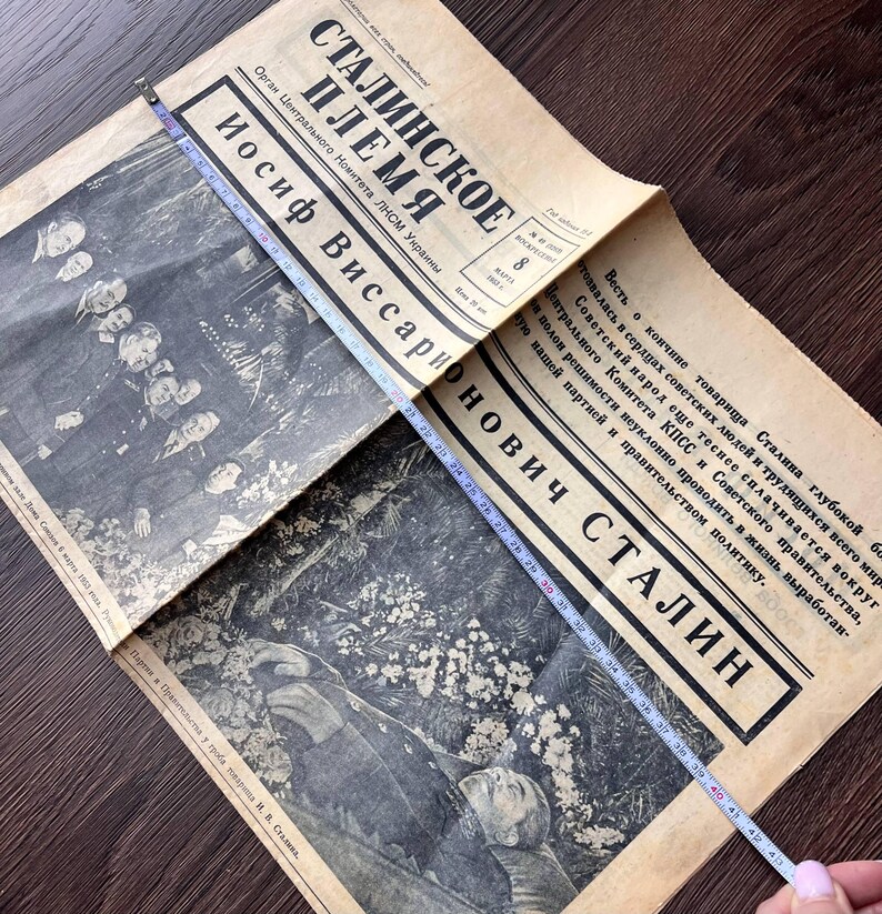 May include: An open vintage newspaper with the headline "STALINSKOE PLEMYA" and the name "IOSIF VISSARIONOVICH STALIN" in bold text. A measuring tape shows the newspaper is approximately 43 inches long. The newspaper has black and white images.
