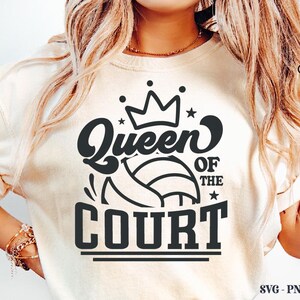 K&ouml;nnte beinhalten: Cremefarbenes T-Shirt mit einem schwarzen Aufdruck, der "Queen of the Court" &uuml;ber einem Volleyball-Design zeigt. Der Text ist mit einer Krone und Sternen gestaltet. Das T-Shirt ist ein Freizeitkleidungsst&uuml;ck.