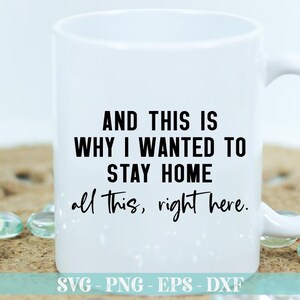 May include: White ceramic mug with black text that reads "AND THIS IS WHY I WANTED TO STAY HOME all this, right here." The mug has a black handle and is sitting on a brown surface.