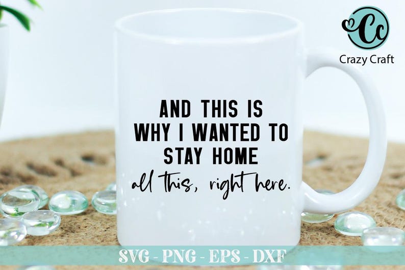 May include: White ceramic mug with black text that reads "AND THIS IS WHY I WANTED TO STAY HOME all this, right here." The mug has a black handle and is sitting on a brown surface.