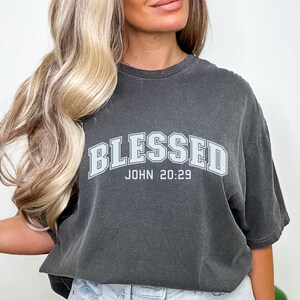 K&ouml;nnte beinhalten: Ein anthrazitfarbenes T-Shirt mit einer wei&szlig;en Grafik, auf der "Blessed John 20:29" steht.