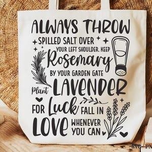 May include: A white canvas tote bag featuring black printed text that reads: ALWAYS THROW SPILLED SALT OVER YOUR LEFT SHOULDER. KEEP ROSEMARY BY YOUR GARDEN GATE. PLANT LAVENDER FOR LUCK. FALL IN LOVE WHENEVER YOU CAN. Includes illustrations of salt.
