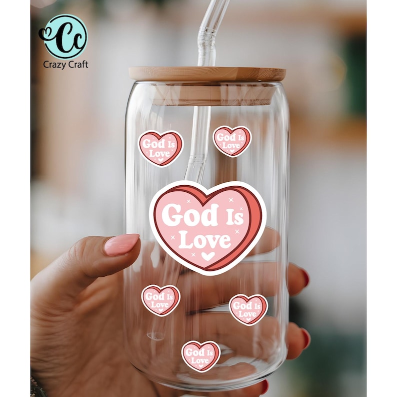 May include: A clear glass tumbler with a wooden lid and a reusable straw. The tumbler is decorated with pink heart-shaped stickers that read "God Is Love." The Crazy Craft logo is in the upper left corner.