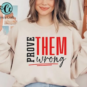 May include: A white sweatshirt with the text "PROVE THEM wrong" printed in black and red. The word "THEM" is in red and the rest of the text is in black.