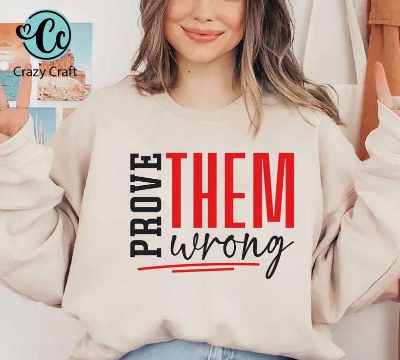 May include: A white sweatshirt with the text "PROVE THEM wrong" printed in black and red. The word "THEM" is in red and the rest of the text is in black.