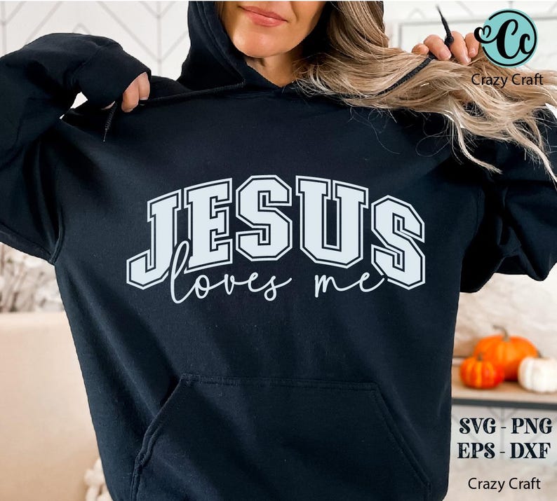 K&ouml;nnte beinhalten: Ein schwarzer Hoodie mit einer wei&szlig;en Grafik, auf der "JESUS loves me" in einer Schriftart im College-Stil steht.