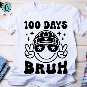 May include: White t-shirt with a black graphic of a smiling face wearing a beanie and sunglasses. The graphic also includes the text "100 DAYS BRUH" in a retro font.