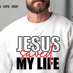 以下が含まれることがあります： 「JESUS saved MY LIFE」の文字が黒と赤でプリントされた白いスウェットシャツ。「JESUS」と「MY LIFE」は太字のブロック体、「saved」は筆記体です。Crazy Craftのロゴも表示されています。