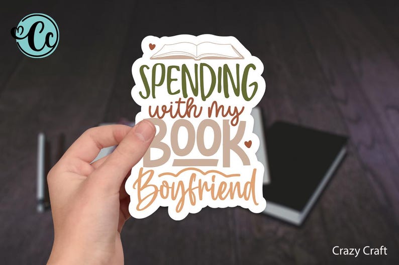 May include: A white sticker with brown and green lettering that reads "Spending with my Book Boyfriend". The sticker features a small open book with a heart above it.