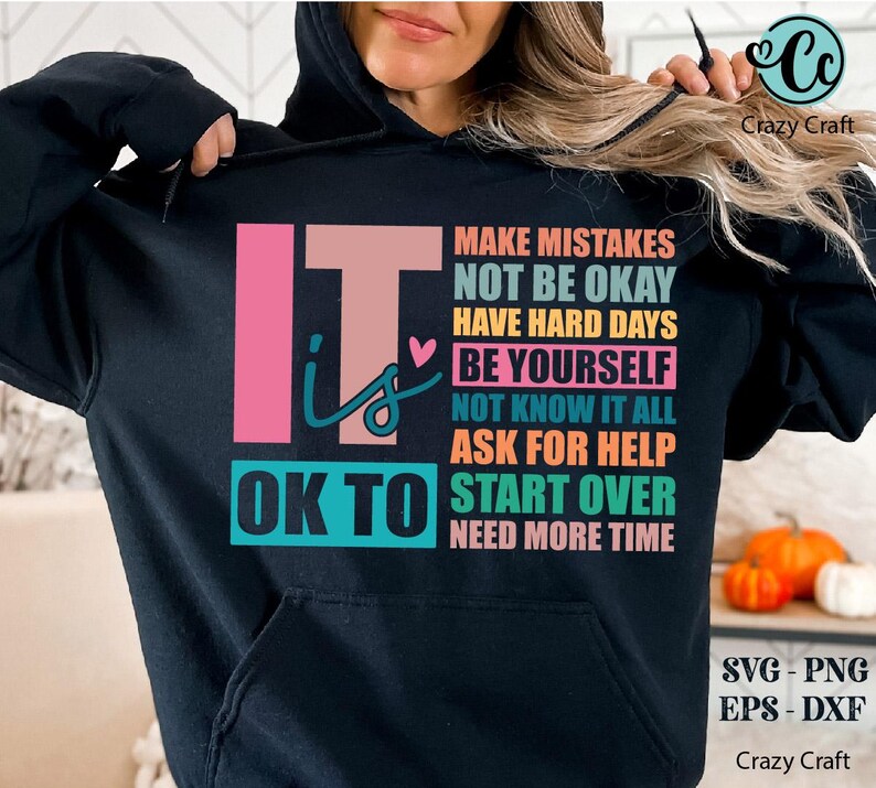 May include: Black hoodie with a colorful graphic that says "It is OK to" and lists a series of phrases including "Make Mistakes", "Not Be Okay", "Have Hard Days", "Be Yourself", "Not Know It All", "Ask For Help", "Start Over", and "Need More Time".