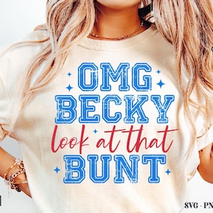 Pode incluir: Camiseta creme com o texto "OMG BECKY look at that BUNT" em azul e vermelho. A camisa apresenta um design desgastado em estilo vintage. O logotipo Crazy Craft é visível no canto superior direito.